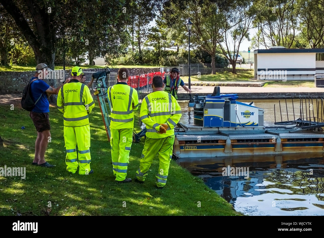 Cormac lavoratori in Hi Viz uniformi in piedi e guardare come un Truxor DM 5045 semovente toolcarrier anfibio è preparato per iniziare a lavorare al con Foto Stock