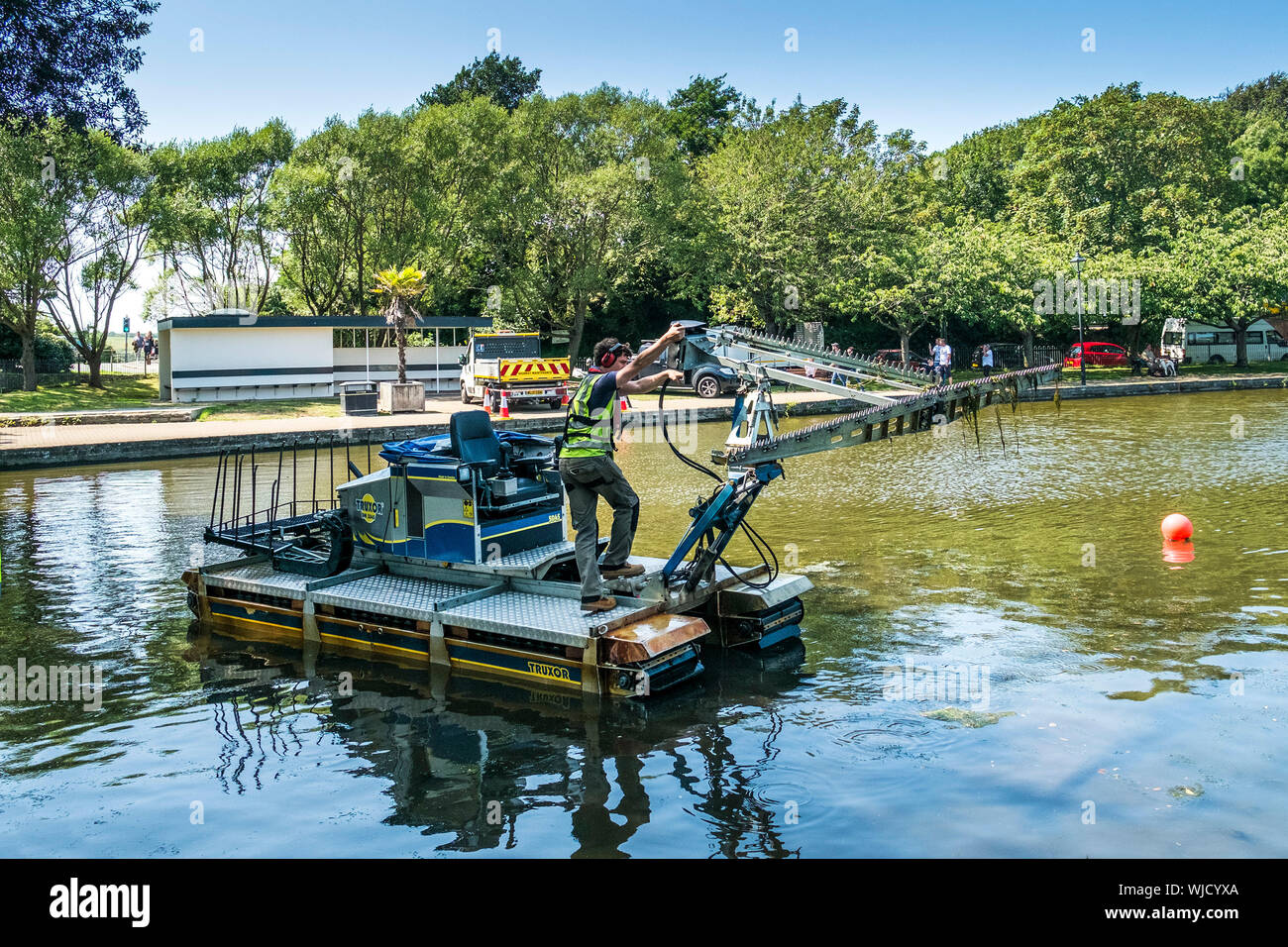 Un Truxor DM 5045 semovente toolcarrier anfibio essendo disposti a lavorare al controllo di vegetazione invasiva Trenance in barca il lago in Newquay in Co Foto Stock