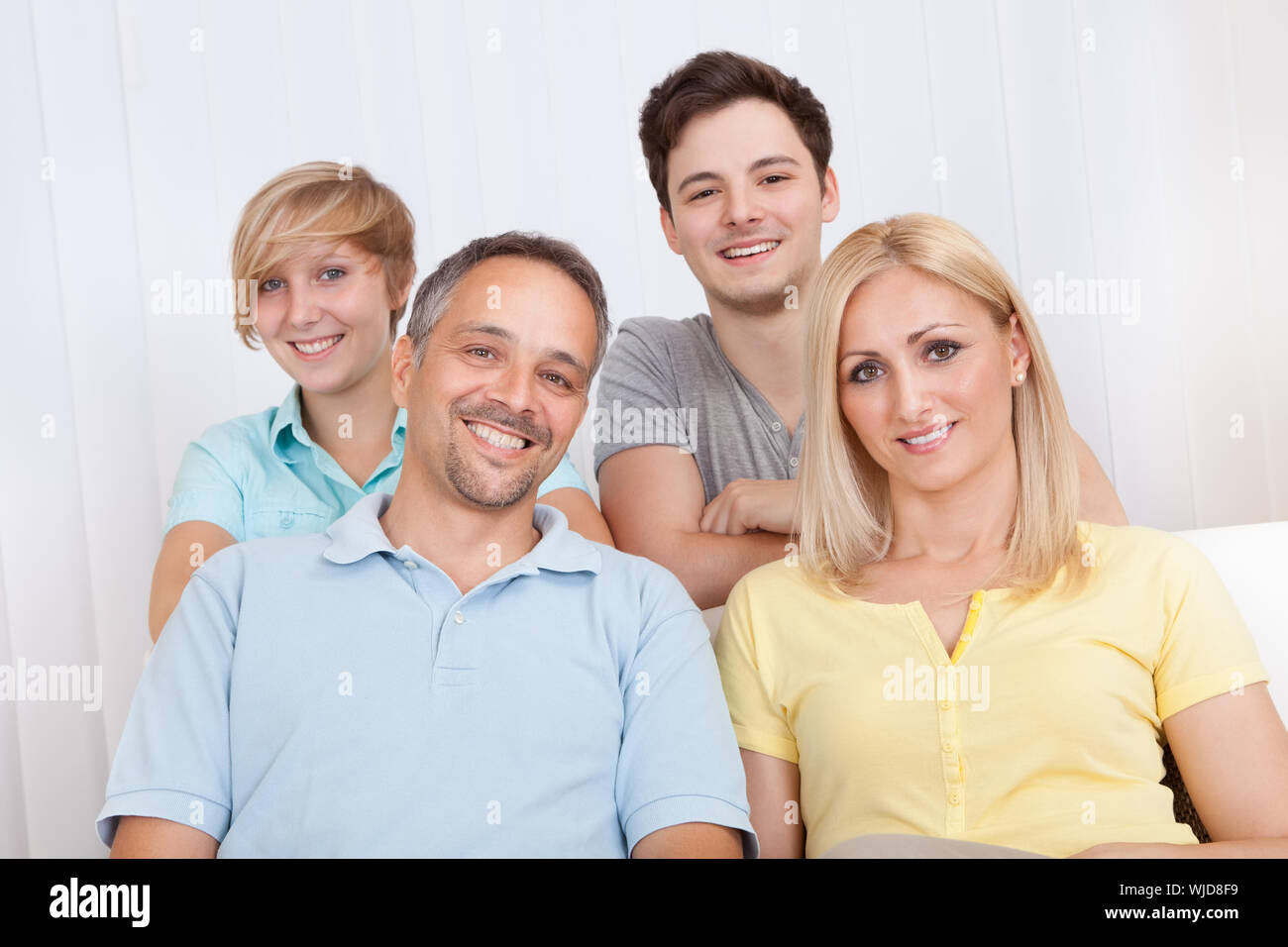 Sorridente attraente di giovani famiglie con un figlio adolescente e figlia in posa insieme nel ritratto di gruppo Foto Stock