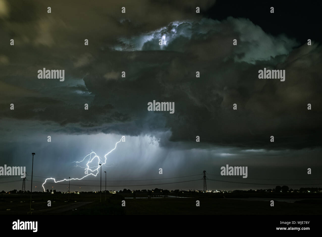 Un potente fulmine colpisce la terra lontano da una spettacolare nube di tuono cumulonimbus Foto Stock
