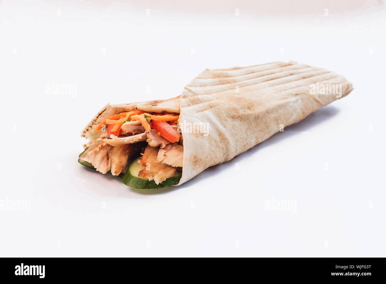 Shawarma isolato con un'ombra. Oriental cibo fatto da carne di pollo, pomodori e cetrioli in pane pita. Foto Stock