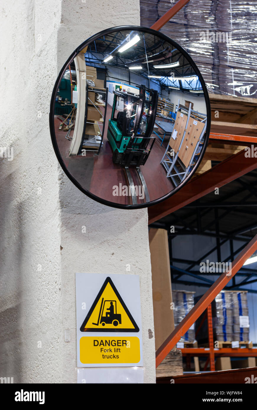Specchio di sicurezza che mostra un riflesso di un carrello elevatore a forche in un magazzino con un 'rabbia carrelli elevatori a forche' firmare al di sotto (verticale). Foto Stock