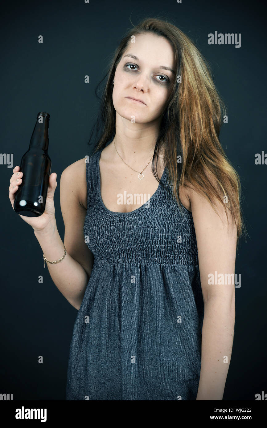 Alcool o droga concetto: sad yound donna con birra guardando la telecamera, dissaturato, tono di ciano. Foto Stock