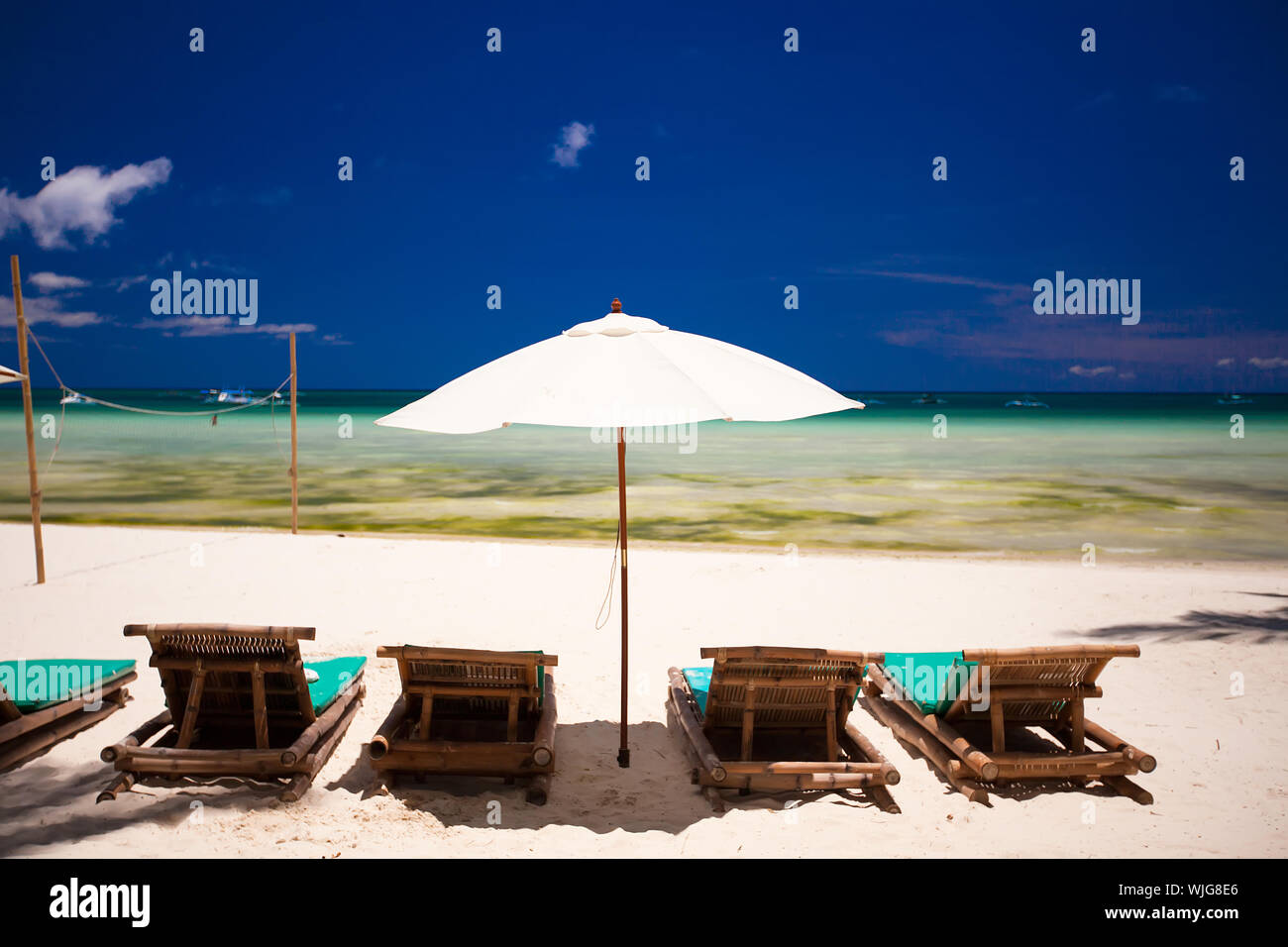 Sedie a sdraio e ombrelloni sulla spiaggia di sabbia bianca di fronte alla laguna Foto Stock