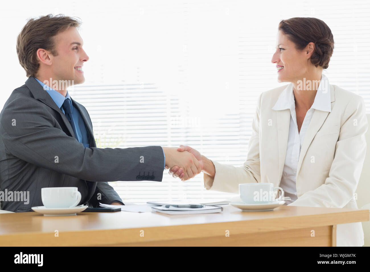 Elegantemente vestito giovane uomo e donna stringono le mani in un incontro di affari in ufficio Foto Stock