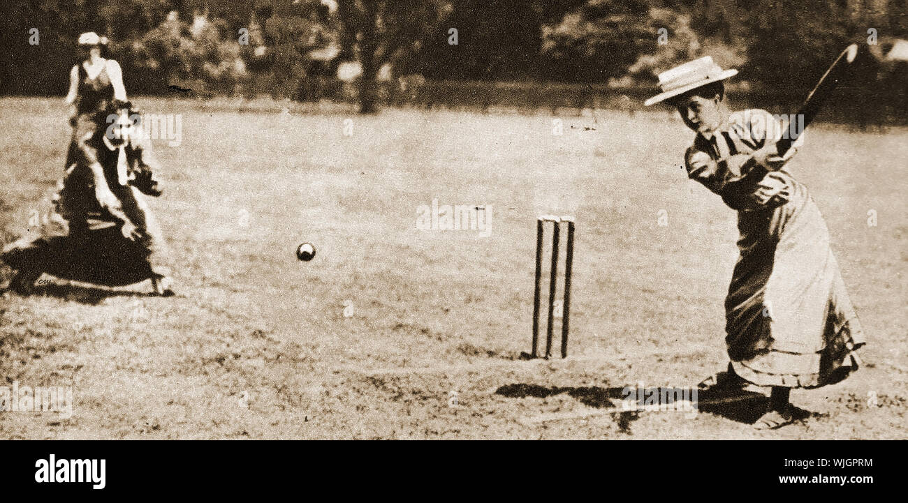 Le donne la riproduzione dello sport tradizionale nel 1911 - femmine a giocare a cricket in contesti formali abiti lunghi e cappelli. Foto Stock