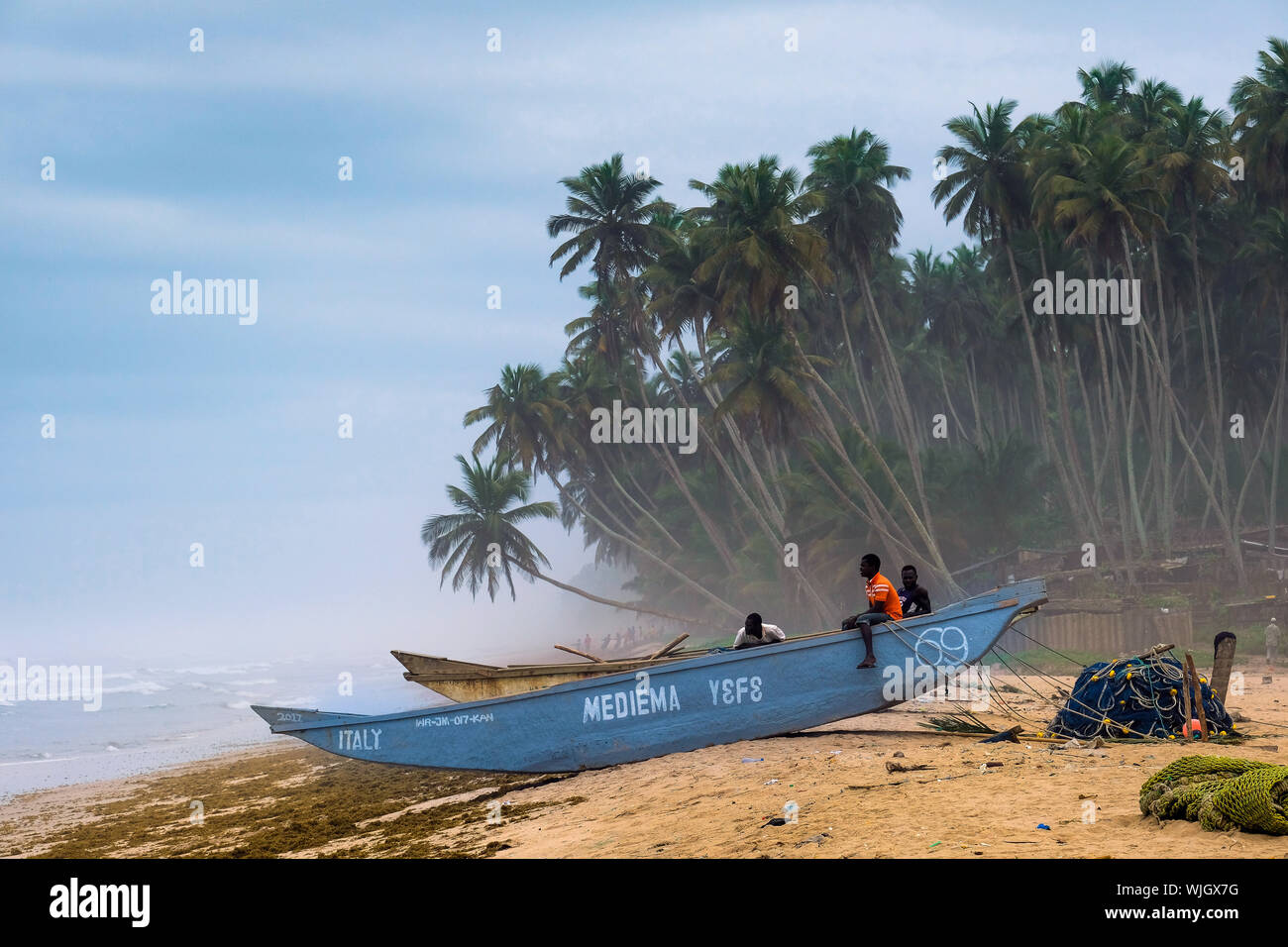 Pescatore su una barca da pesca in spiaggia rurale del villaggio di pescatori Kengen, Ghana, Africa occidentale Foto Stock