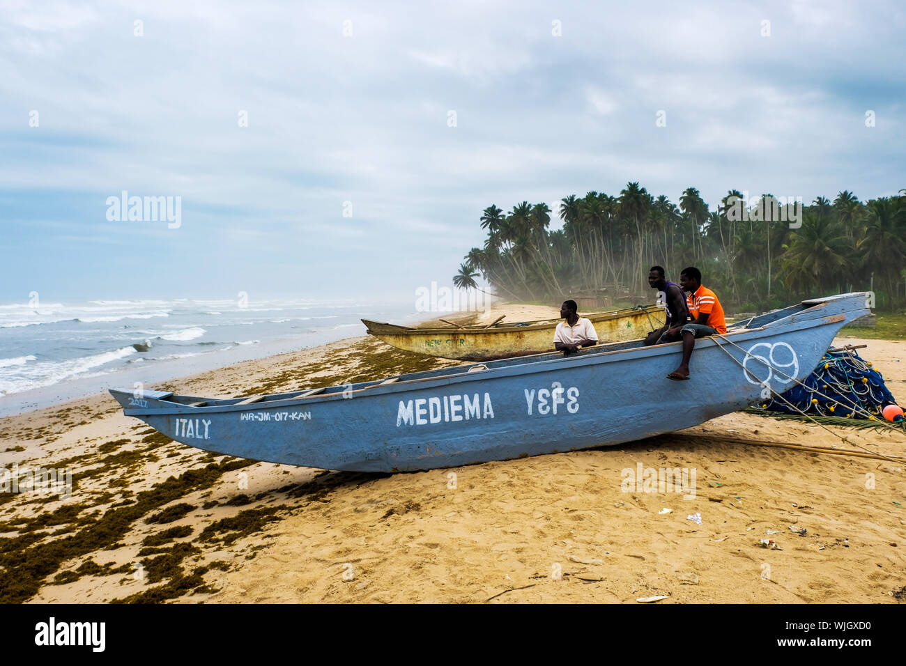 Pescatore su una barca da pesca in spiaggia rurale del villaggio di pescatori Kengen, Ghana, Africa occidentale Foto Stock