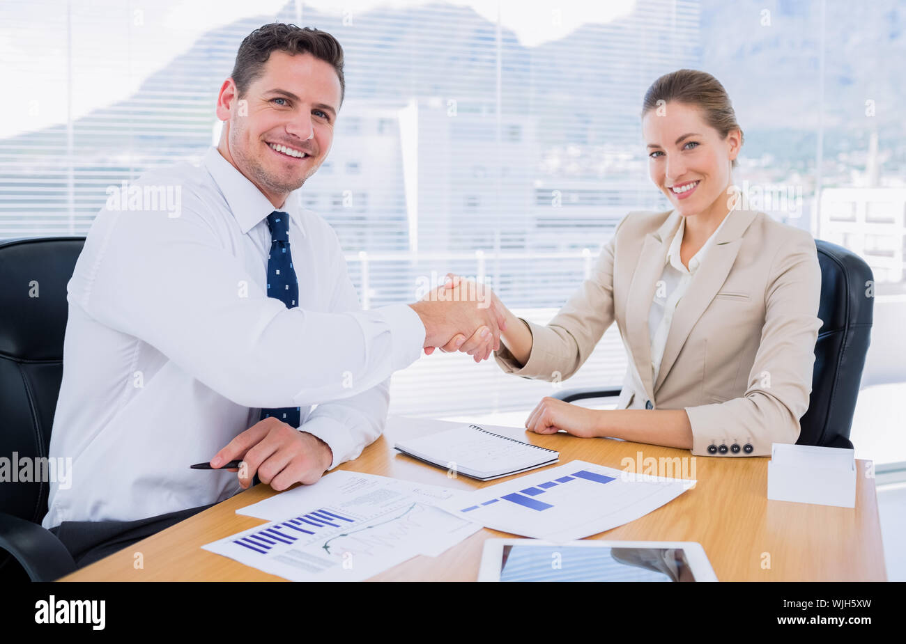Elegantemente vestito giovane uomo e donna stringono le mani in un incontro di affari in ufficio Foto Stock