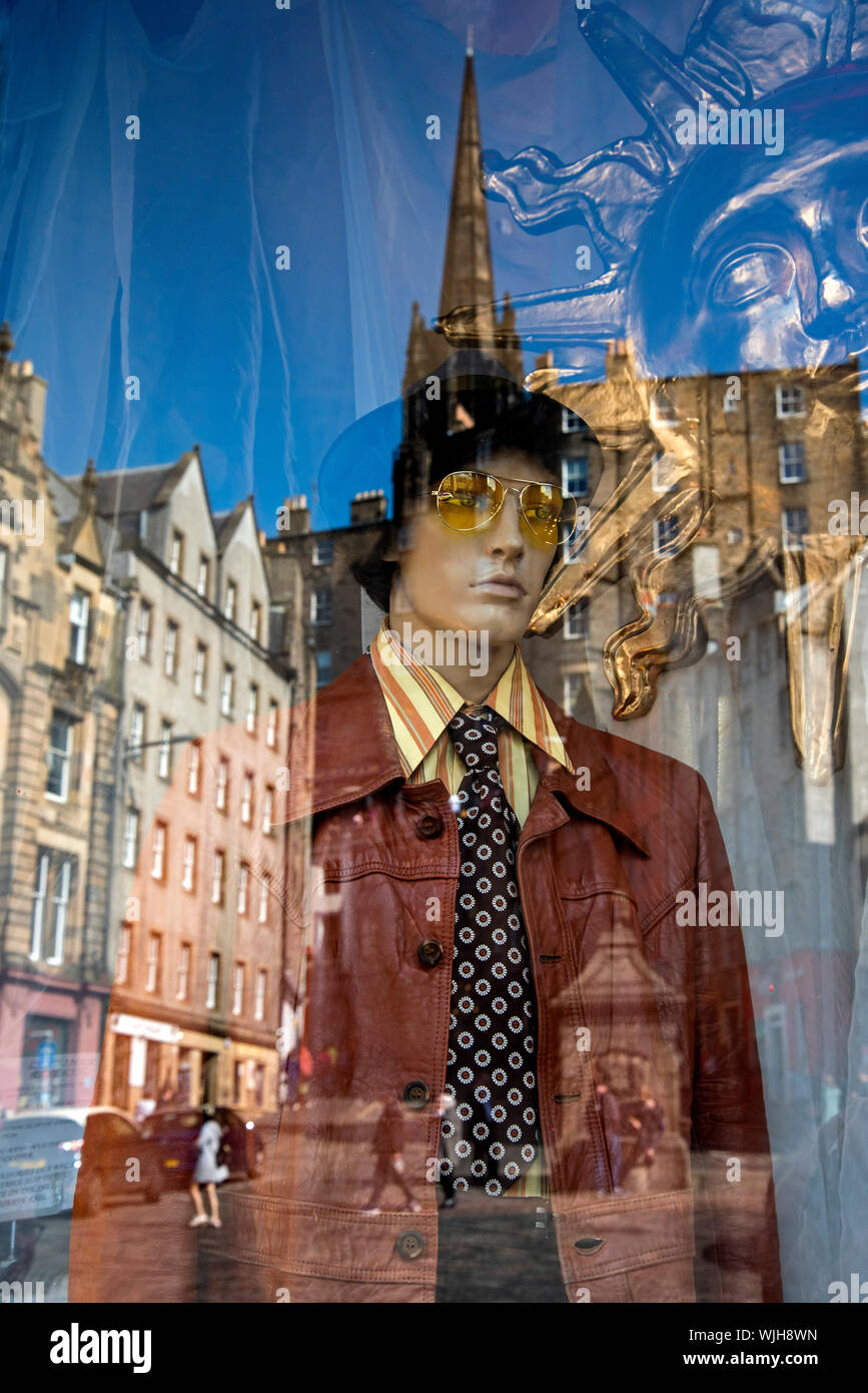 Le riflessioni dal Grassmarket nella finestra di Armstrong abbigliamento Vintage Emporium, Edimburgo, Scozia, Regno Unito. Foto Stock