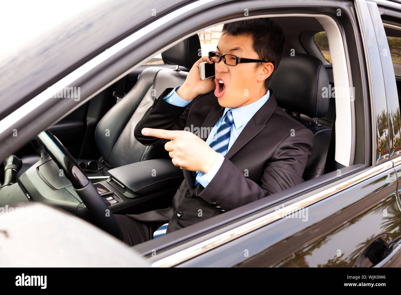 Imprenditore infuriate parlando con un telefono cellulare in auto Foto Stock