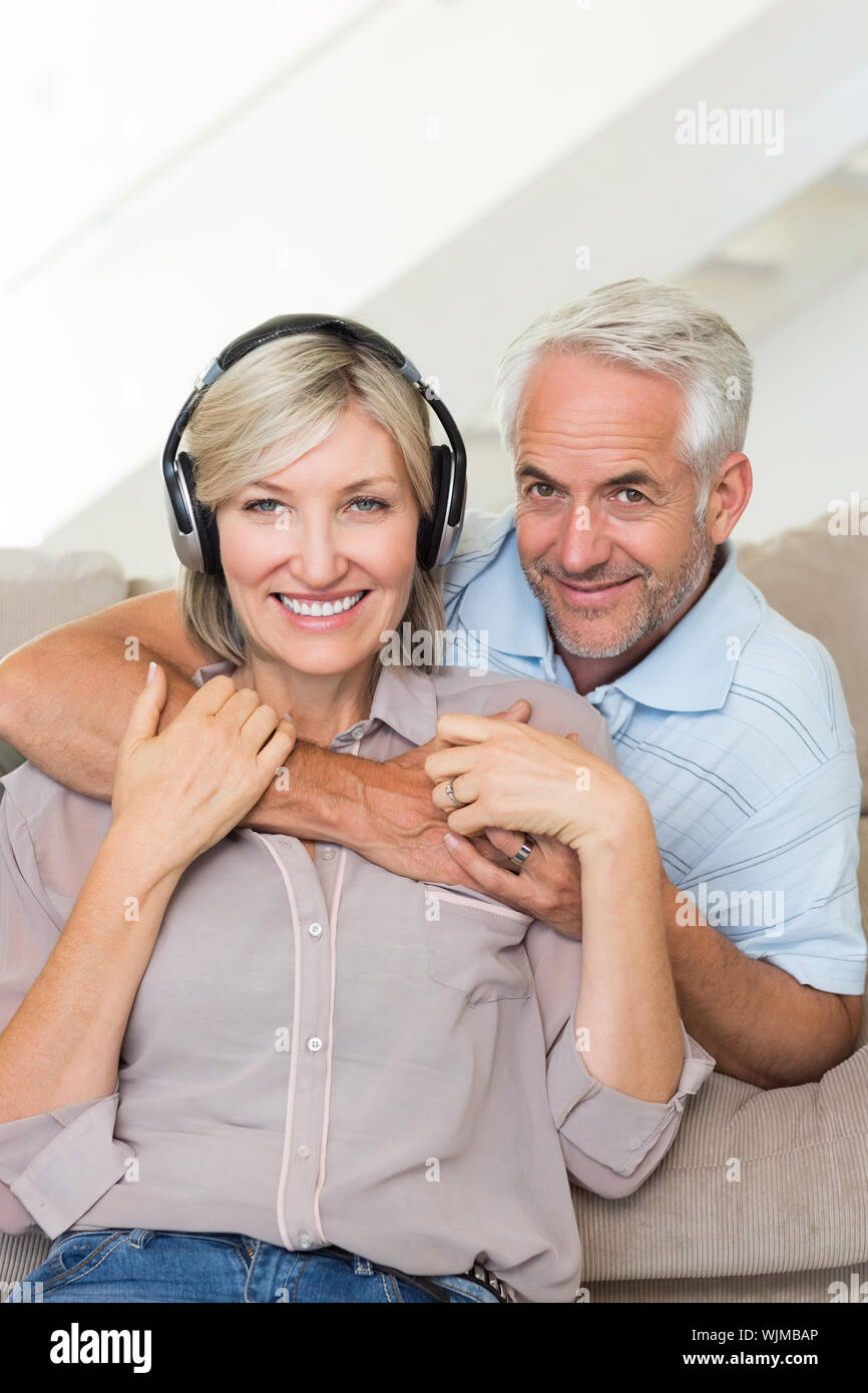 Sorridente uomo maturo abbracciando la donna da dietro sul divano di casa Foto Stock