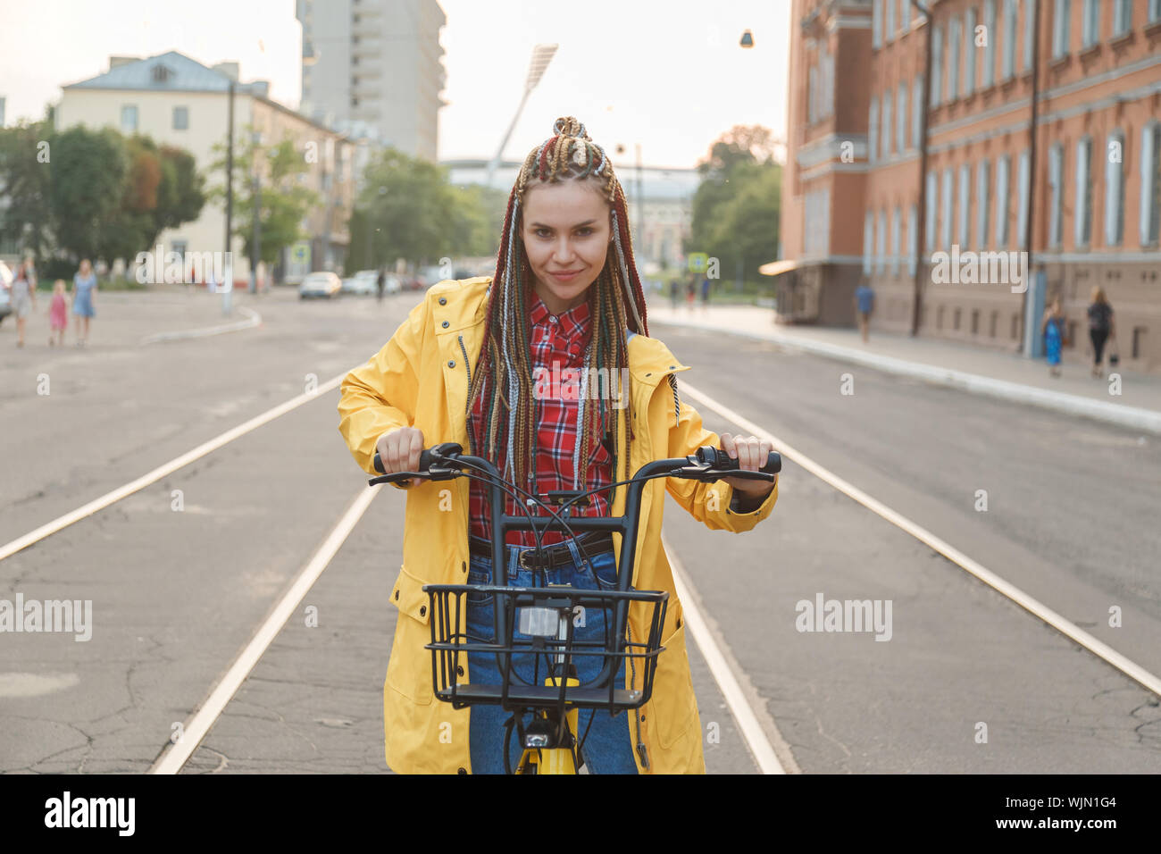 Ritratto di Pretty girl in giallo ricoprire seduti sulla bici Foto Stock