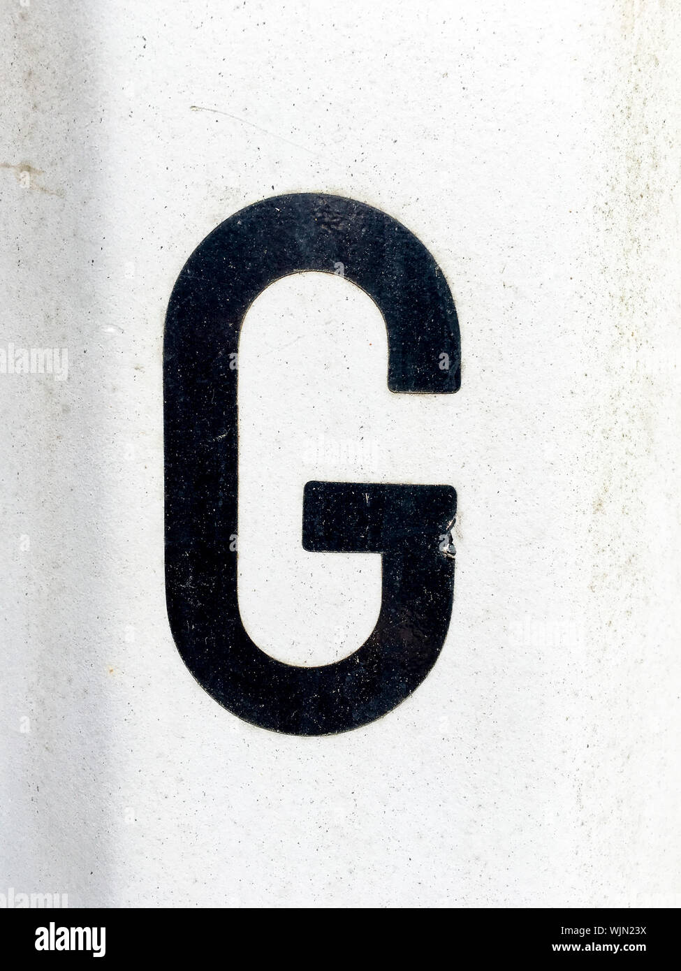 Close-up di Lettera nera G sul muro bianco Foto Stock