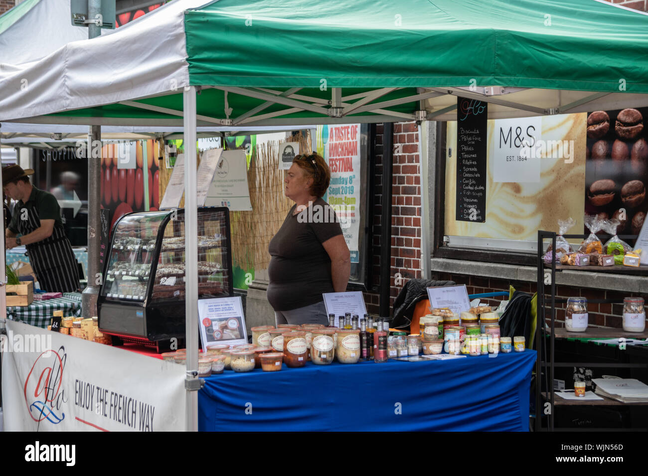 Winchester, Hampshire, Regno Unito un mercato titolare di stallo in piedi dietro di lei in attesa di stallo per i clienti Foto Stock