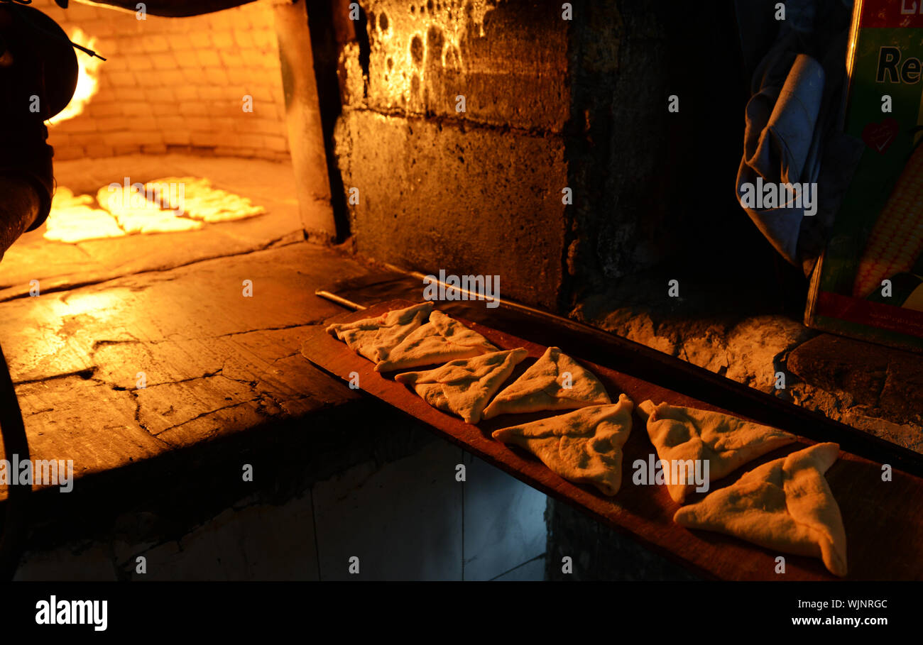 Un panettiere Giordani cottura Sambousek tradizionale in un forno a fuoco in Madaba, Giordania. Foto Stock