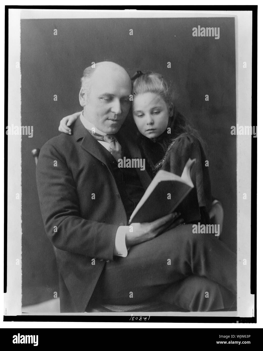 Howard Pyle, tre quarti di lunghezza verticale, seduto, rivolta leggermente a destra, guardando il libro, e sua figlia Phoebe con il braccio attorno alle sue spalle Foto Stock