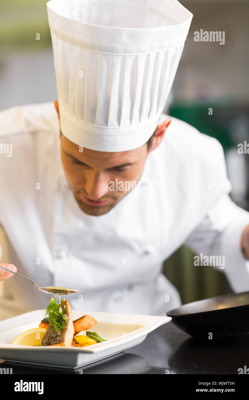 Primo piano di un concentrato maschio guarnitura dello chef in cucina il cibo Foto Stock