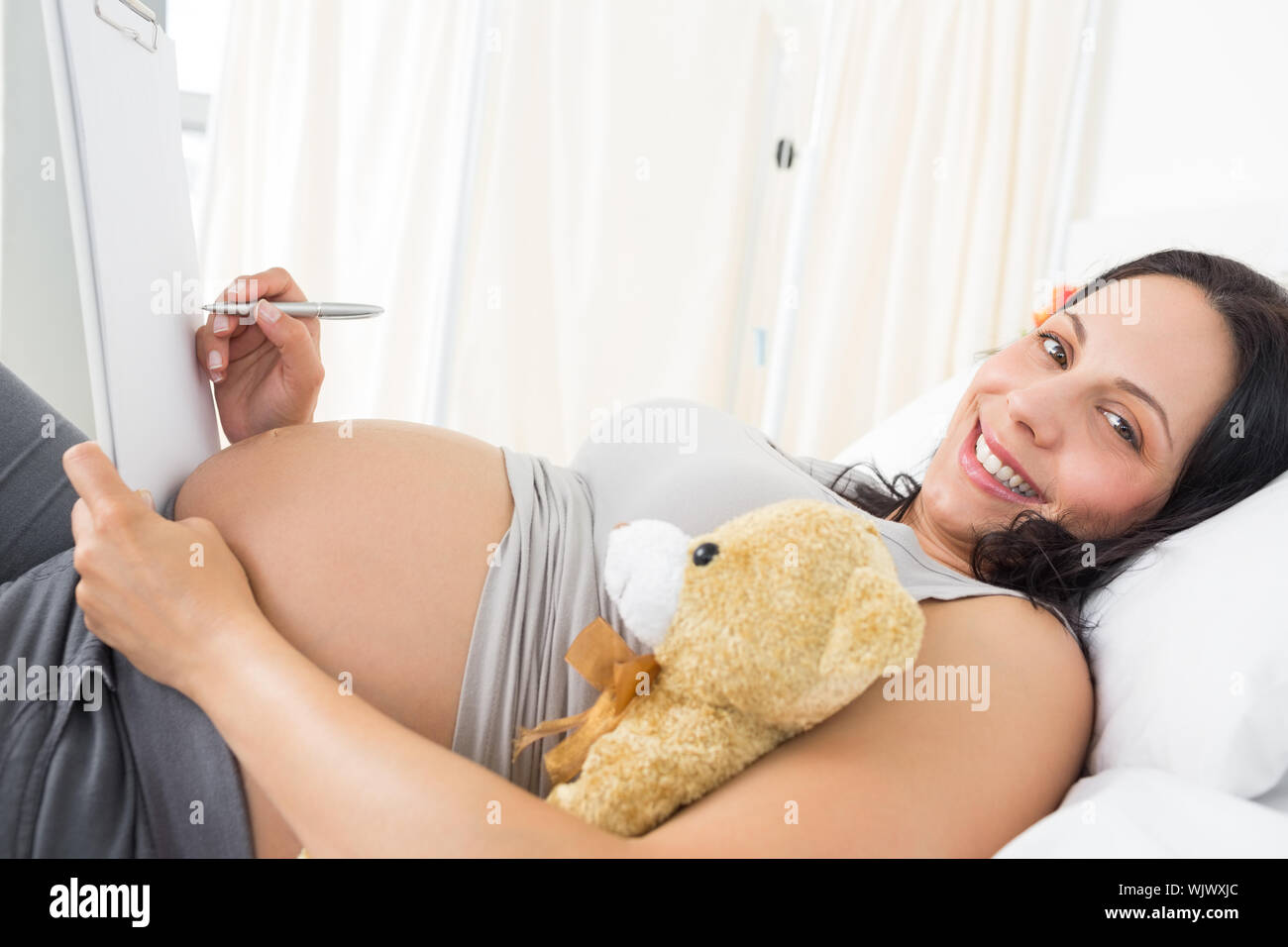 Ritratto di felice donna incinta iscritto negli appunti in ospedale Foto Stock