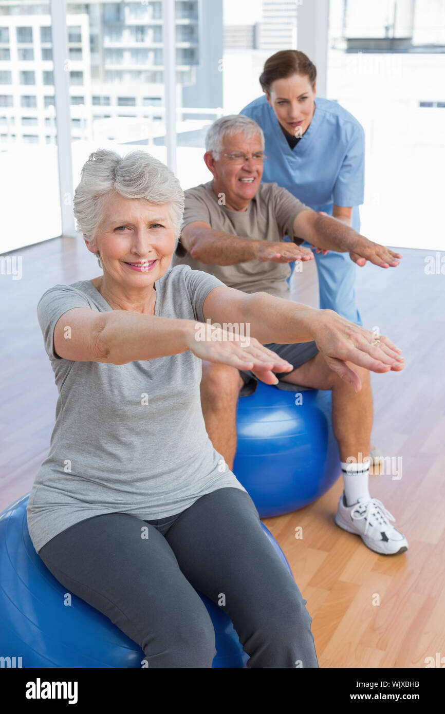 Terapista del sesso femminile aiutando coppia senior con esercizi in ufficio medico Foto Stock