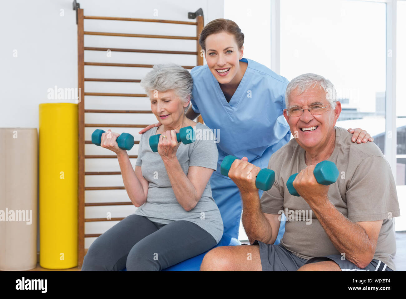 Terapista del sesso femminile aiutando coppia senior con manubri in ufficio medico Foto Stock