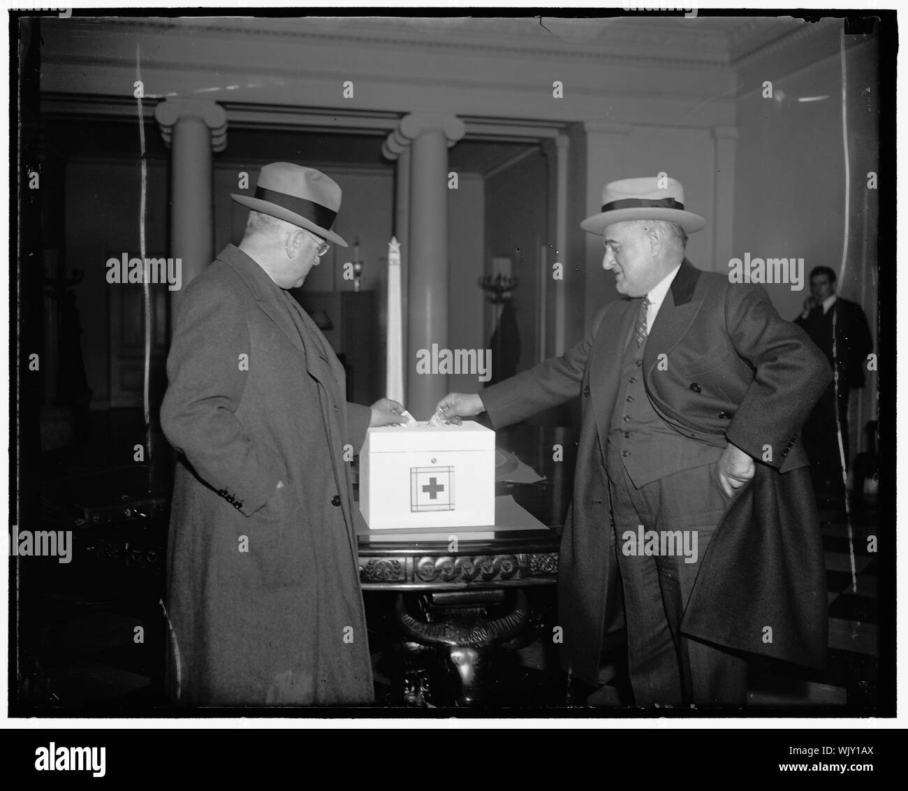 Ickes e Senatore Guffey goccia contributi in soccorso alluvione casella nella Casa Bianca. Washington D.C. I chiamanti sul presidente Roosevelt oggi è ricordato al pubblico il problema nel diluvio situazione. Un smaltato bianco petto, circa le dimensioni di una scatola di pane, è stato messo su un tavolo nella lobby degli uffici dirigenziali per ricevere contributi alluvione. Il Segretario degli Interni Harold Ickes (sinistra) e il senatore Joseph Guffey, della Pennsylvania, raffigurato come fanno cadere i loro contributi nella casella Foto Stock