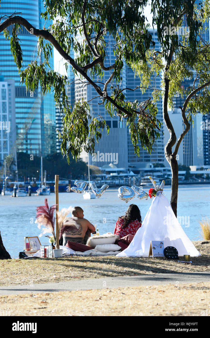 Coppia avente un picnic romantico lungo il Fiume Brisbane a Kangaroo Point, Brisbane, Queensland, QLD, Australia Foto Stock