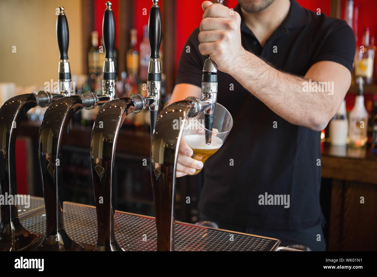 Barman tirando una pinta di birra Foto Stock