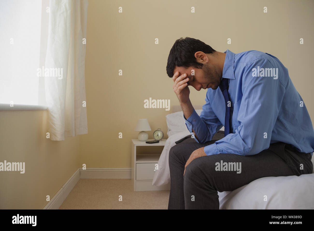 Luttuosi uomo seduto in testa le mani sul suo letto Foto Stock