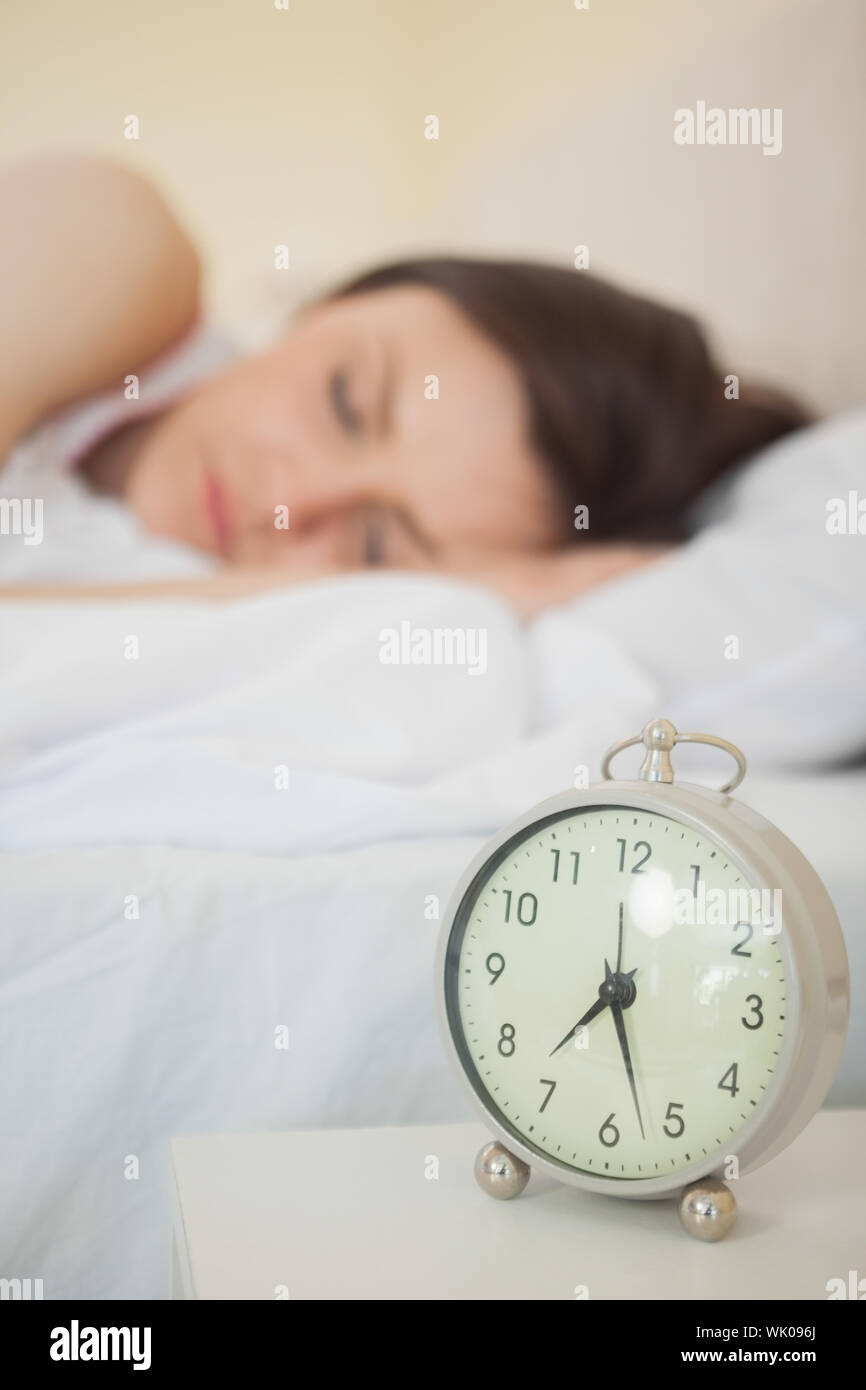 Ragazza dorme nel suo letto con una sveglia in primo piano Foto Stock