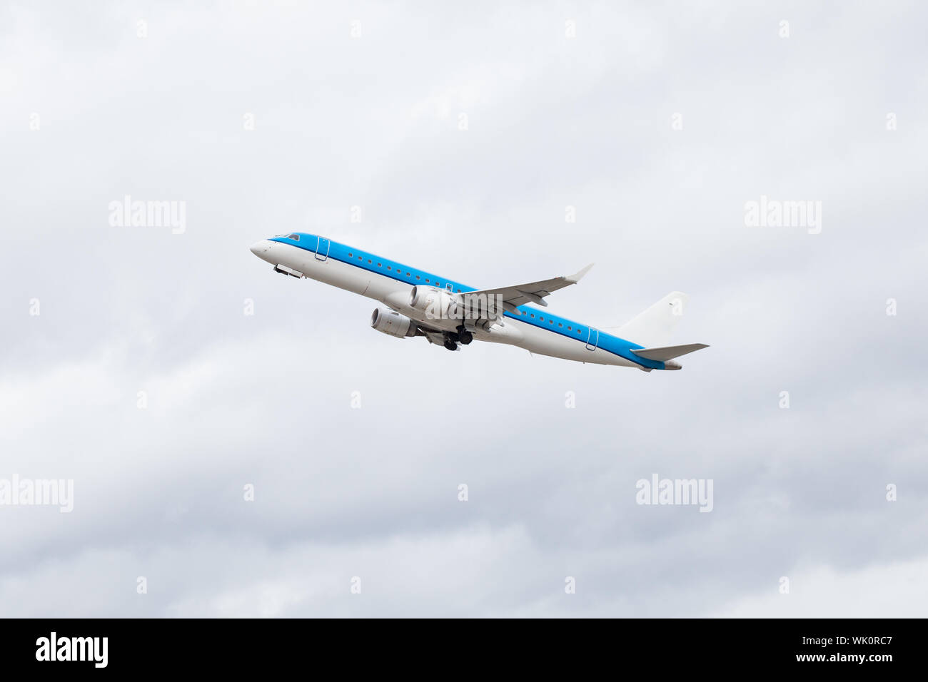 Aereo commerciale battenti midair dopo il decollo con il carrello di atterraggio e ruote comunque estesa come si inerpica per altezza contro un cielo blu, concettuale Foto Stock