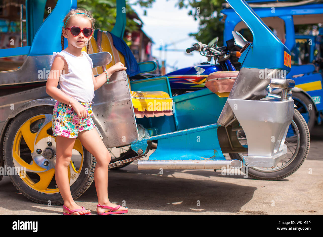 Bambina vicino a trasporto locale threecycles nel paese asiatico Foto Stock