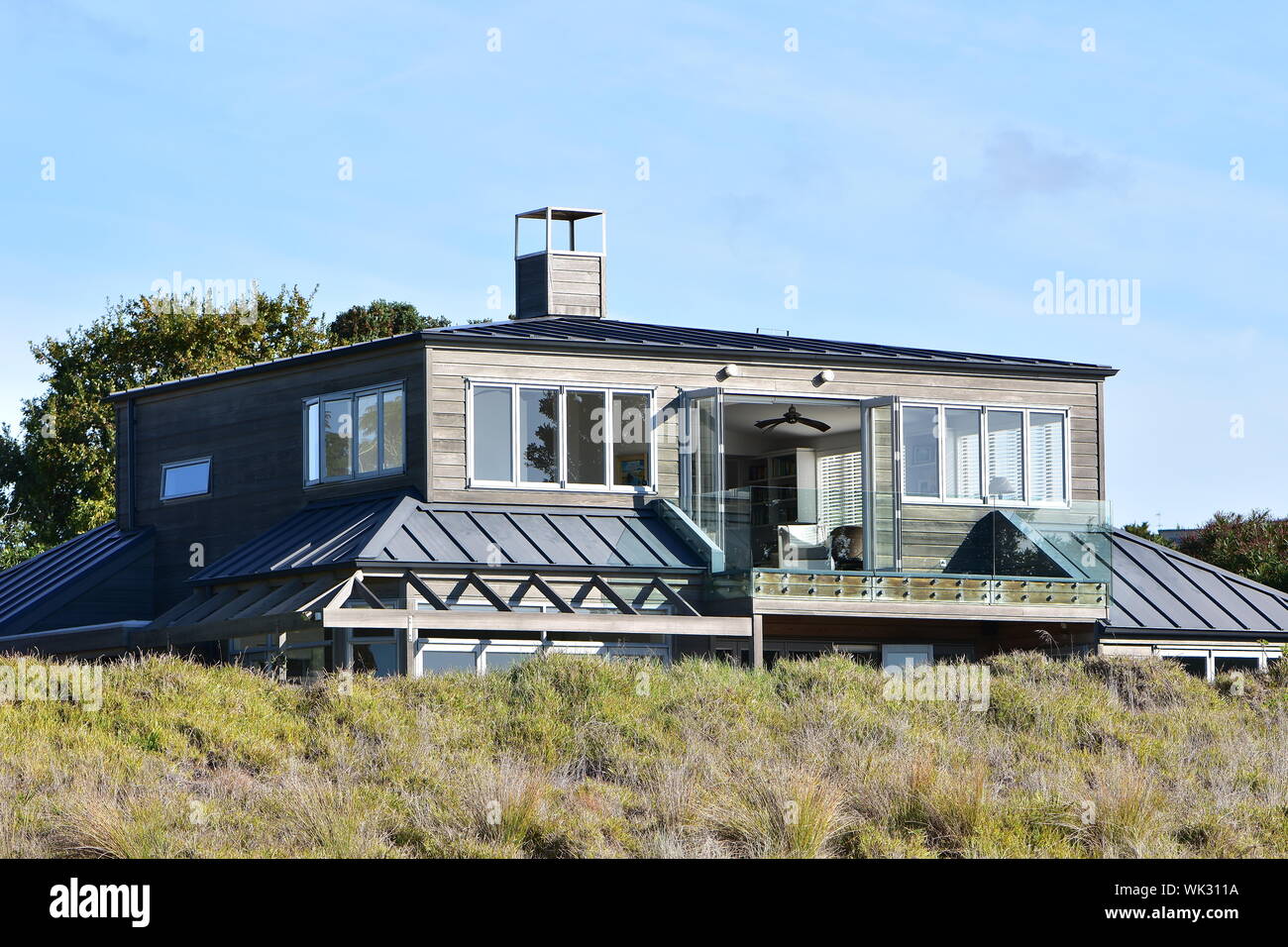 Moderna casa in legno protetta dal vento da dune ancora permettendo buone vedute dalla storia superiore. Foto Stock