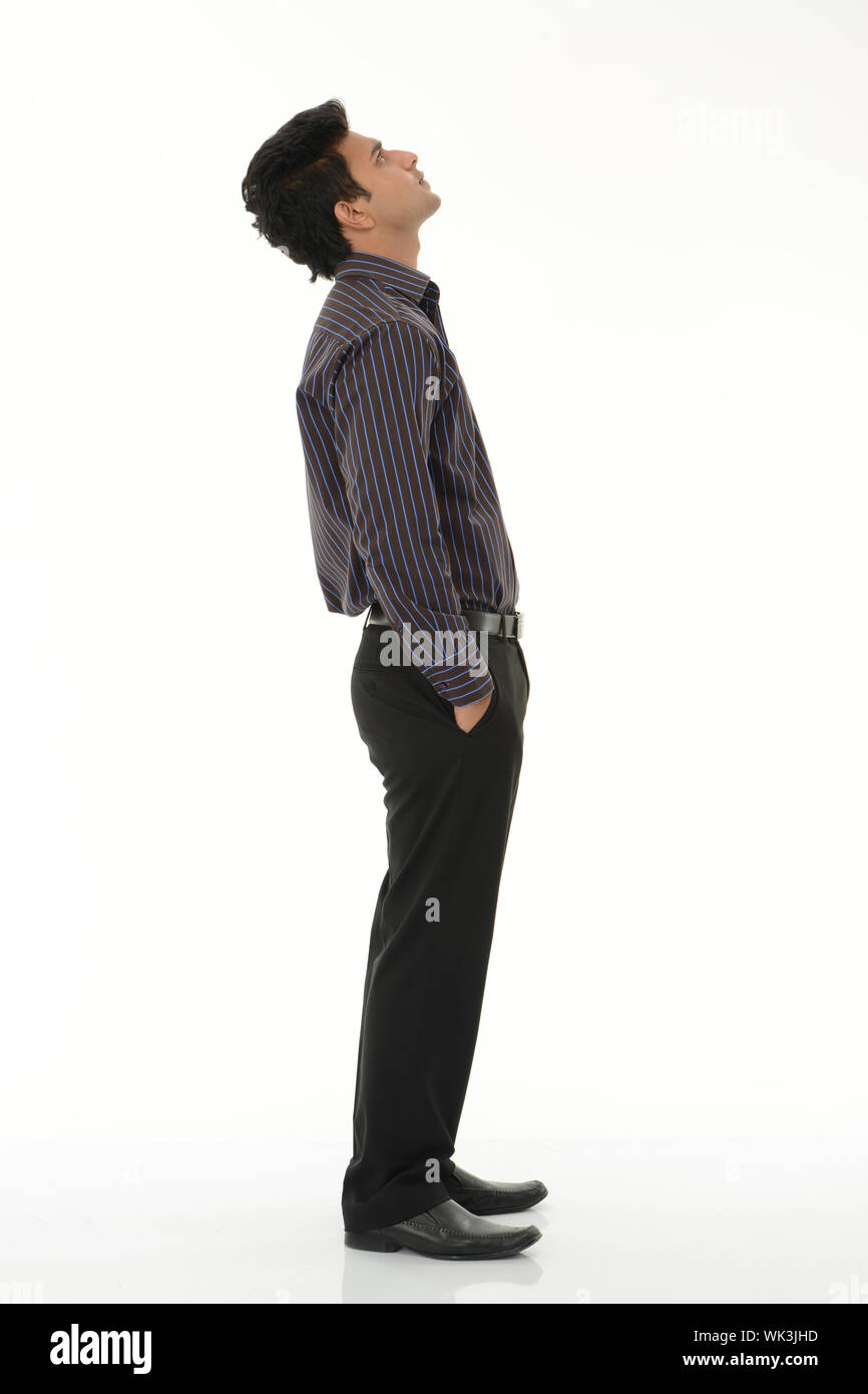 Profilo laterale di un giovane uomo in piedi con le mani nelle tasche Foto Stock