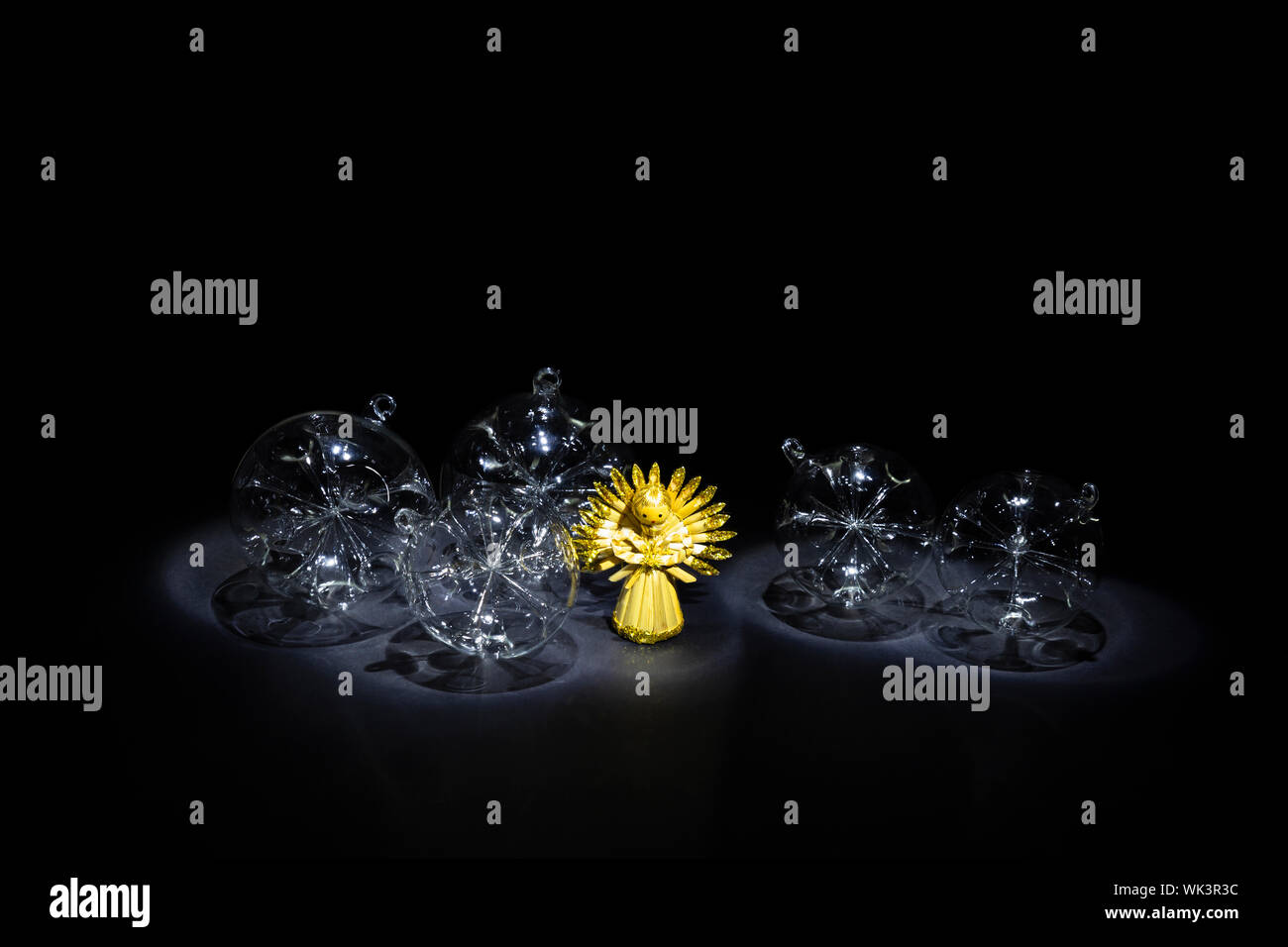 Disposizione della bella mano di vetro trasparente di palle di Natale e un simpatico angelo paglia su sfondo nero Foto Stock