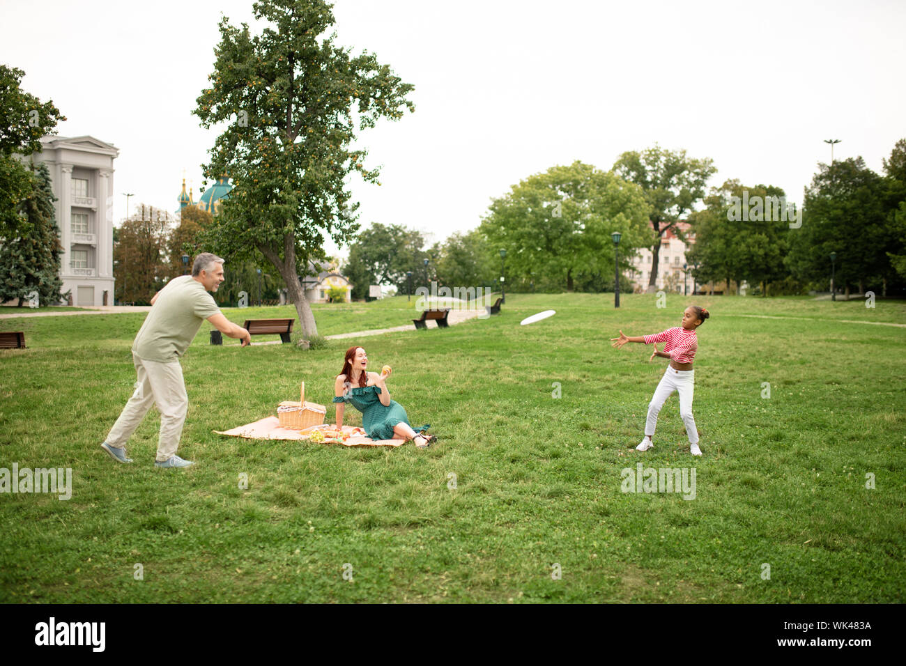 Famiglia giocando frisbee pur avendo picnic nel parco Foto Stock