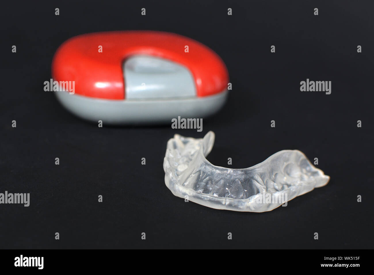 Trasparenti personalizzati denti dentale bite guard allineatori trasparenti per la ganascia inferiore nella parte anteriore del caso sfocate su nero scuro Foto Stock