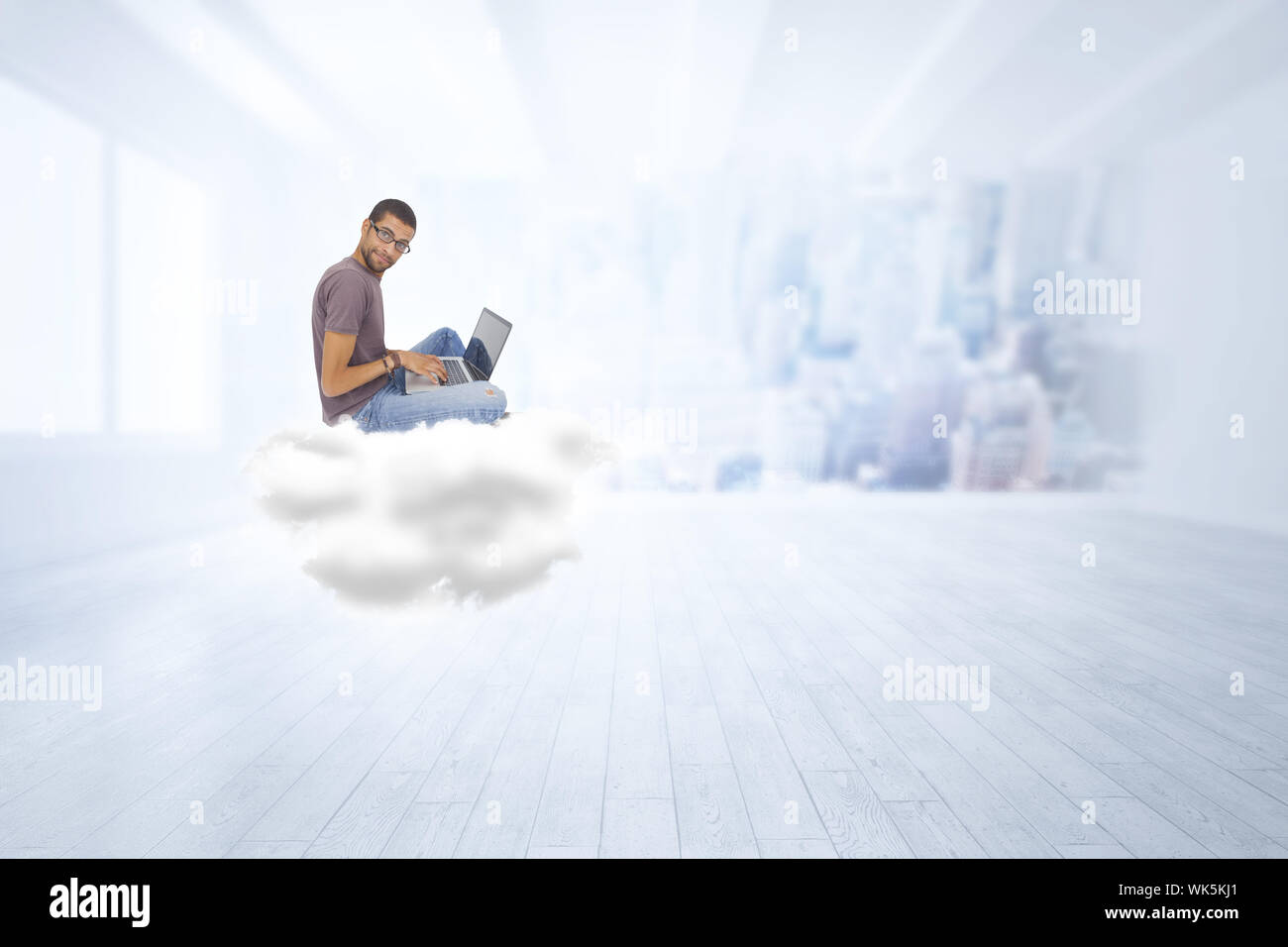 Uomo con gli occhiali seduto sulla nuvola utilizzando laptop e guardando la telecamera contro la città di scena in una stanza Foto Stock