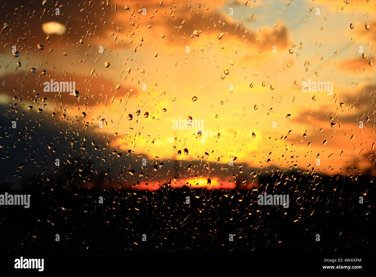 La pioggia al di fuori della finestra sul background del tramonto. Gocce di pioggia sul vetro durante la pioggia. Tramonto al di fuori finestra durante la pioggia. Texture brillanti di gocce di acqua Foto Stock