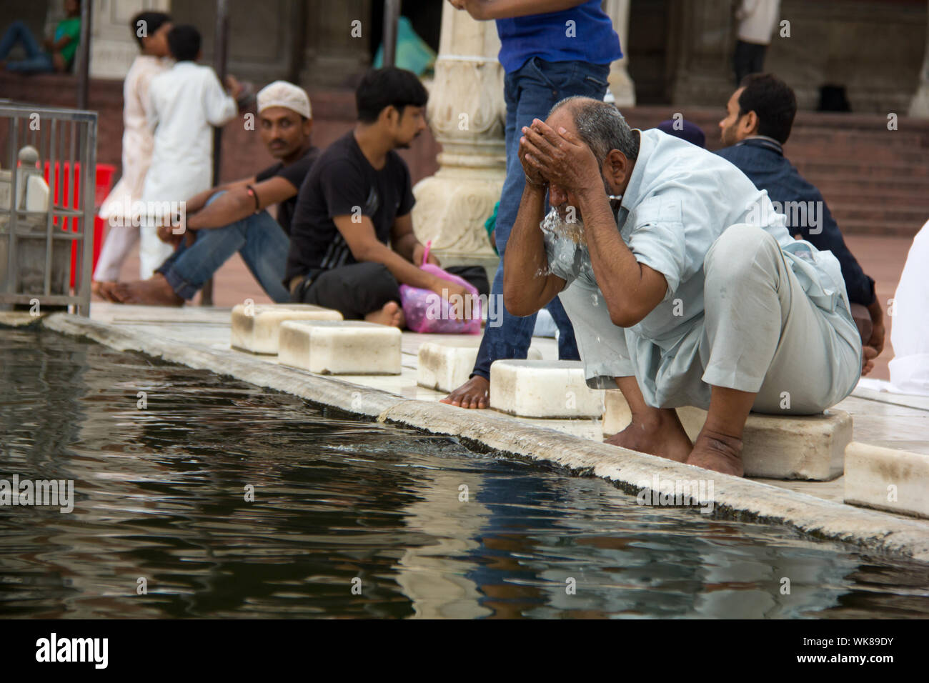 Senior uomo eseguire wudhu rituale prima namaz a una moschea Jama Masjid, la Vecchia Delhi, India Foto Stock