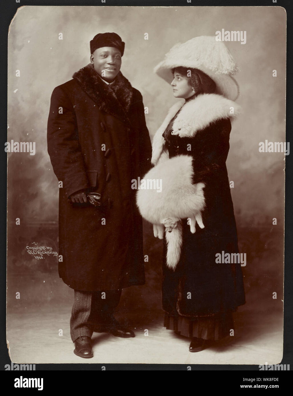 Jack Johnson e sua moglie Etta di intera lunghezza verticale, piedi, indossando cappotti invernali Foto Stock