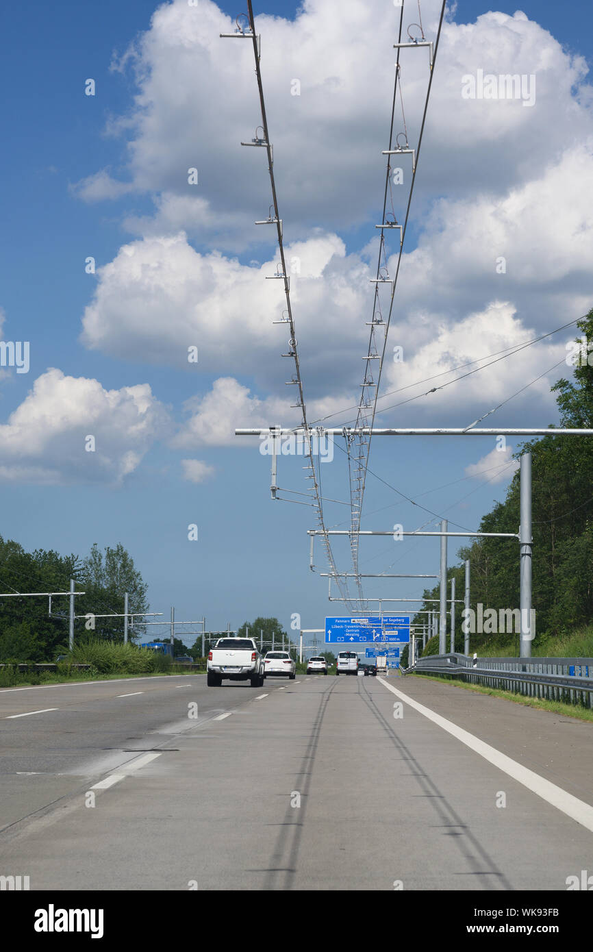 E-autostrada con sovraccarico elettrico filo di contatto per ibrido camion, test in pista a Lubecca, Germania, cielo blu con nuvole, spazio copia, verticale, selezionato Foto Stock
