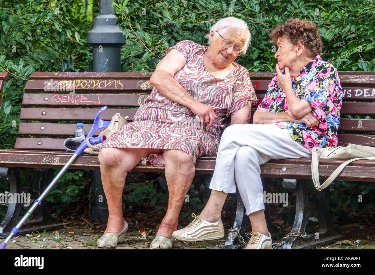 Due donne anziane sedute su una panchina del parco, anziani Foto Stock