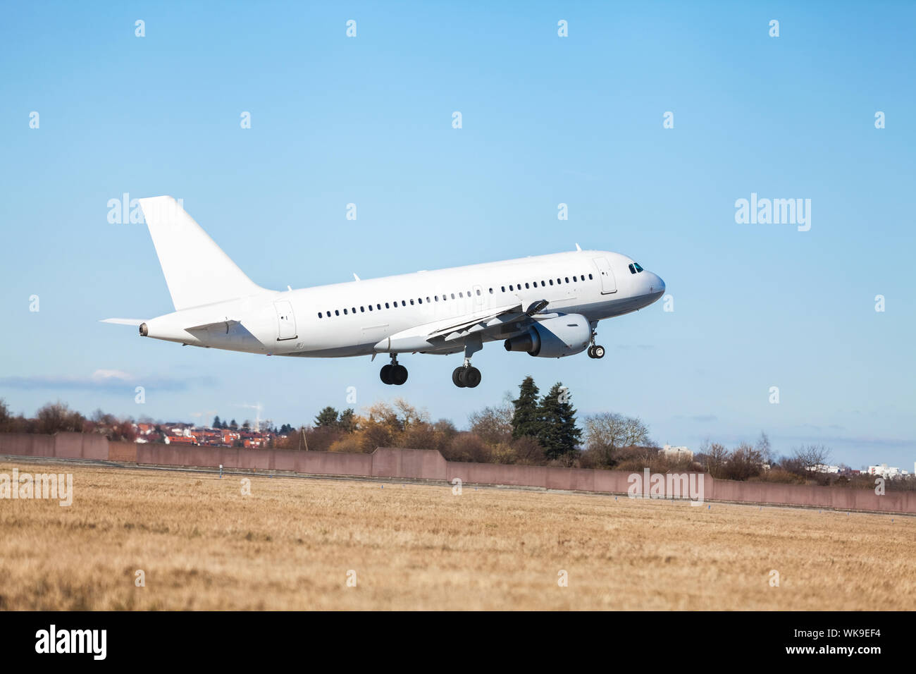 Aereo di linea di passeggeri di decollare in un aeroporto chiaro di sollevamento della pista di fronte al terminal, vista laterale Foto Stock