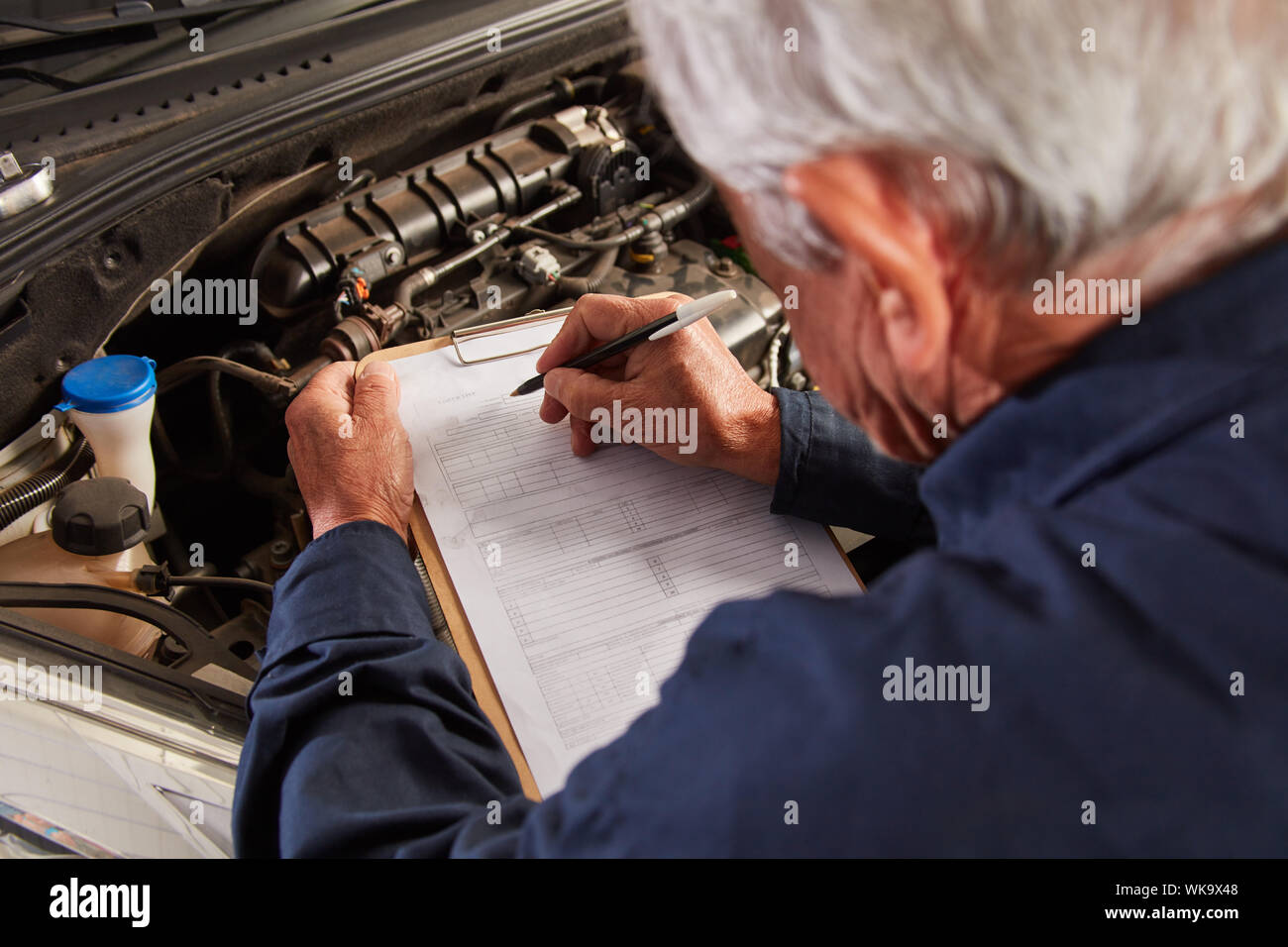 Meccanico con un elenco di controllo di ispezione principale o di ispezione al negozio di riparazioni auto Foto Stock