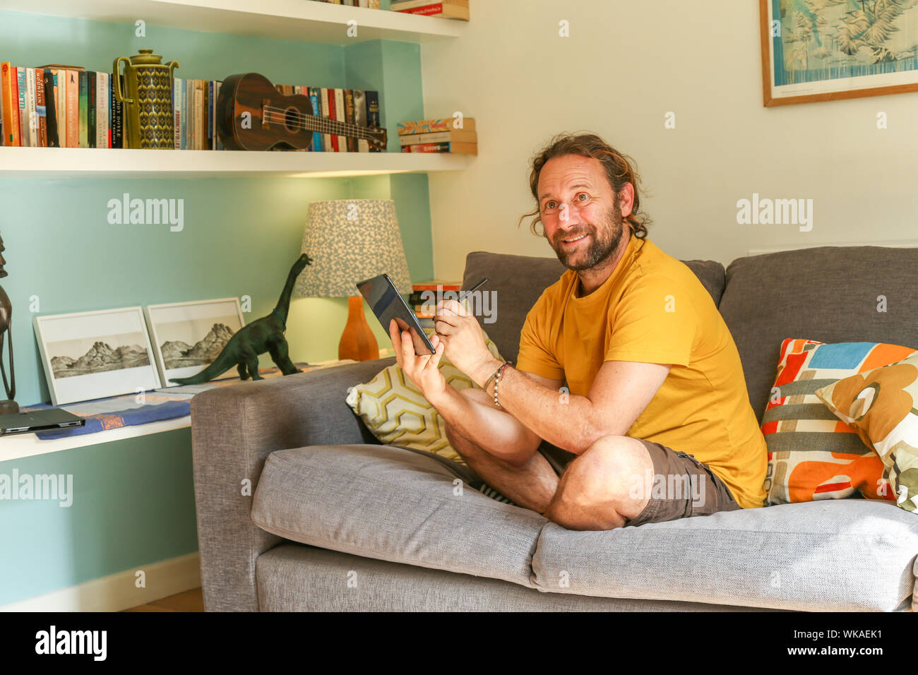 Uomo caucasico 40-50 usando Tab S Samsung Galaxy tablet in casa al coperto sul divano. Foto Stock