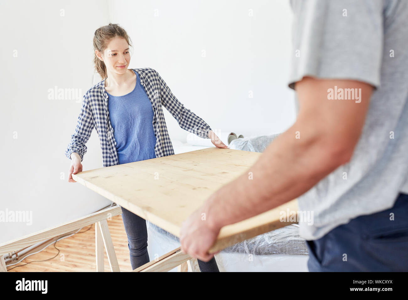 La donna aiuta il suo amico con la creazione di una tabella mentre si sposta nel nuovo appartamento Foto Stock