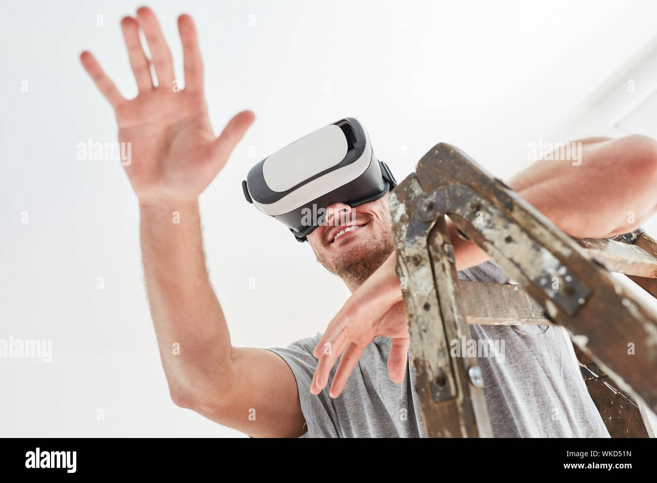 L'uomo come un tuttofare con occhiali VR nello spazio virtuale di pianificazione e progettazione di interni Foto Stock