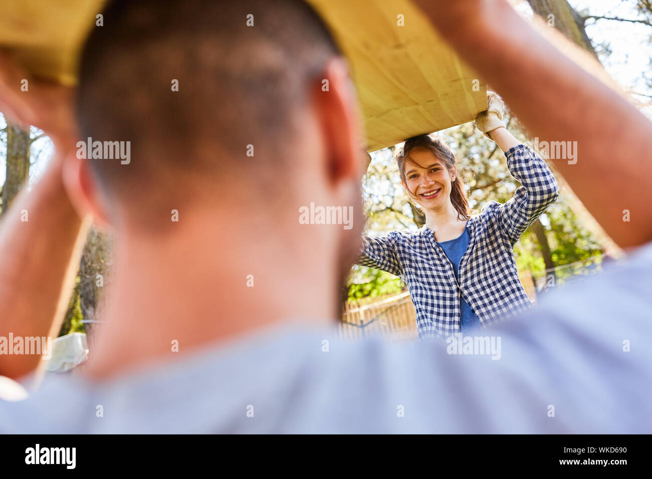 Coppia giovane insieme portano un tavolo o una tavola di legno per la loro nuova casa Foto Stock