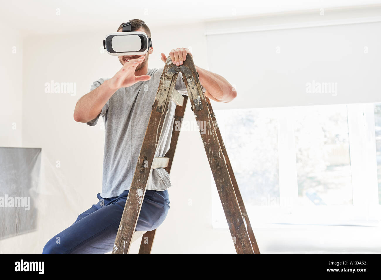 Giovane Uomo con occhiali VR rende virtual interior design durante i lavori di ristrutturazione nella nuova casa Foto Stock